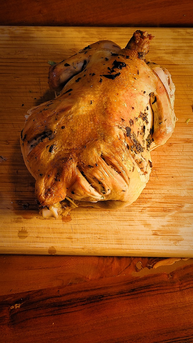Image of a cooked chicken resting on a wooden cutting board.